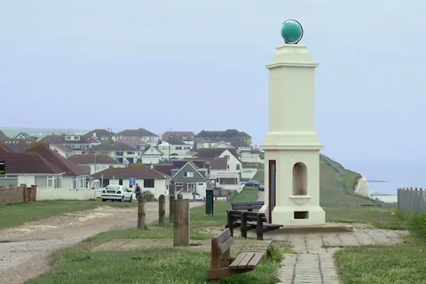 Columna blanca con globo verde junto al paseo costero de Peacehaven