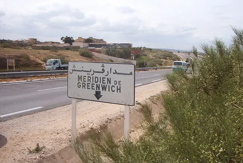 Panel en árabe y francés del meridiano de Greenwich junto a la carretera de Stidia