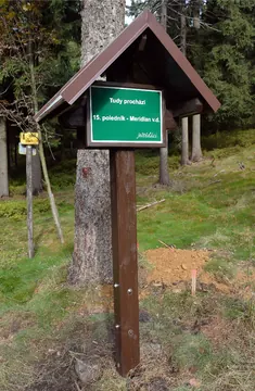 Poste de madera con tejadillo y placa verde del meridiano 15 este en Ještěd