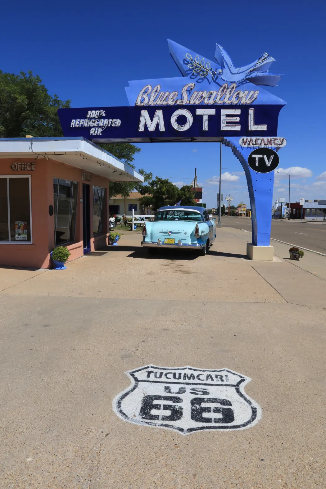 Rótulo de neón, coche clásico y escudo pintado del Blue Swallow Motel en Tucumcari