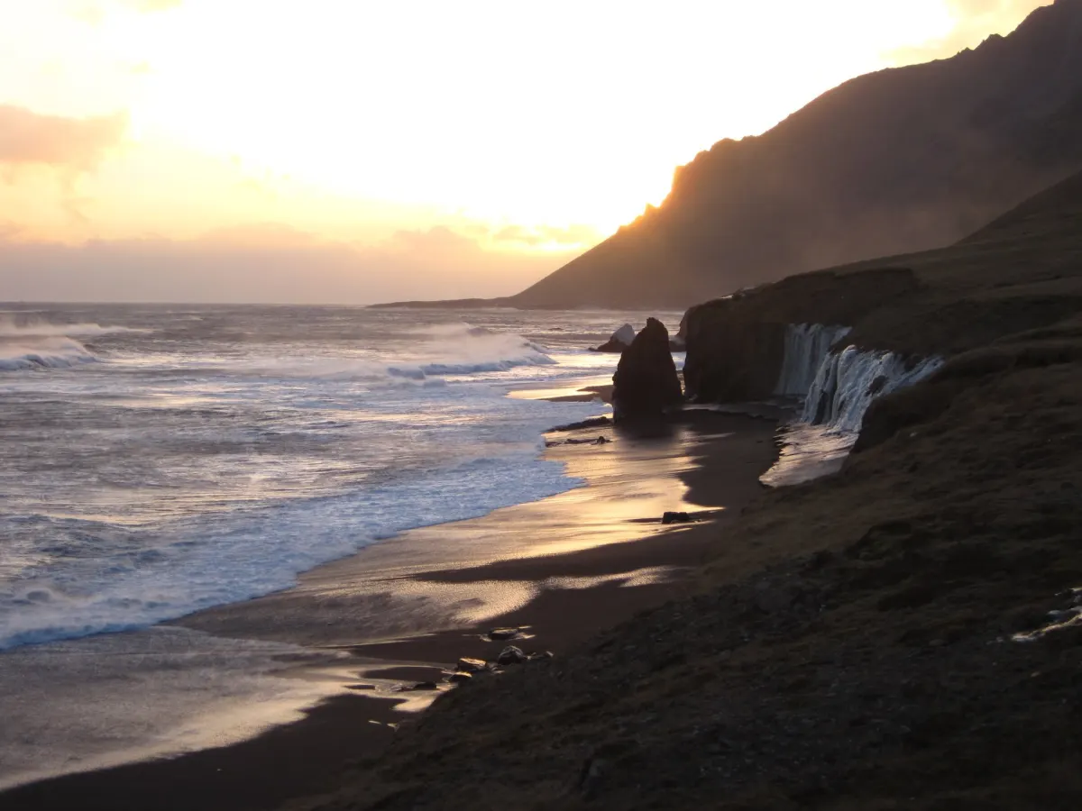 Costa de arena negra con cascadas y acantilados en Islandia