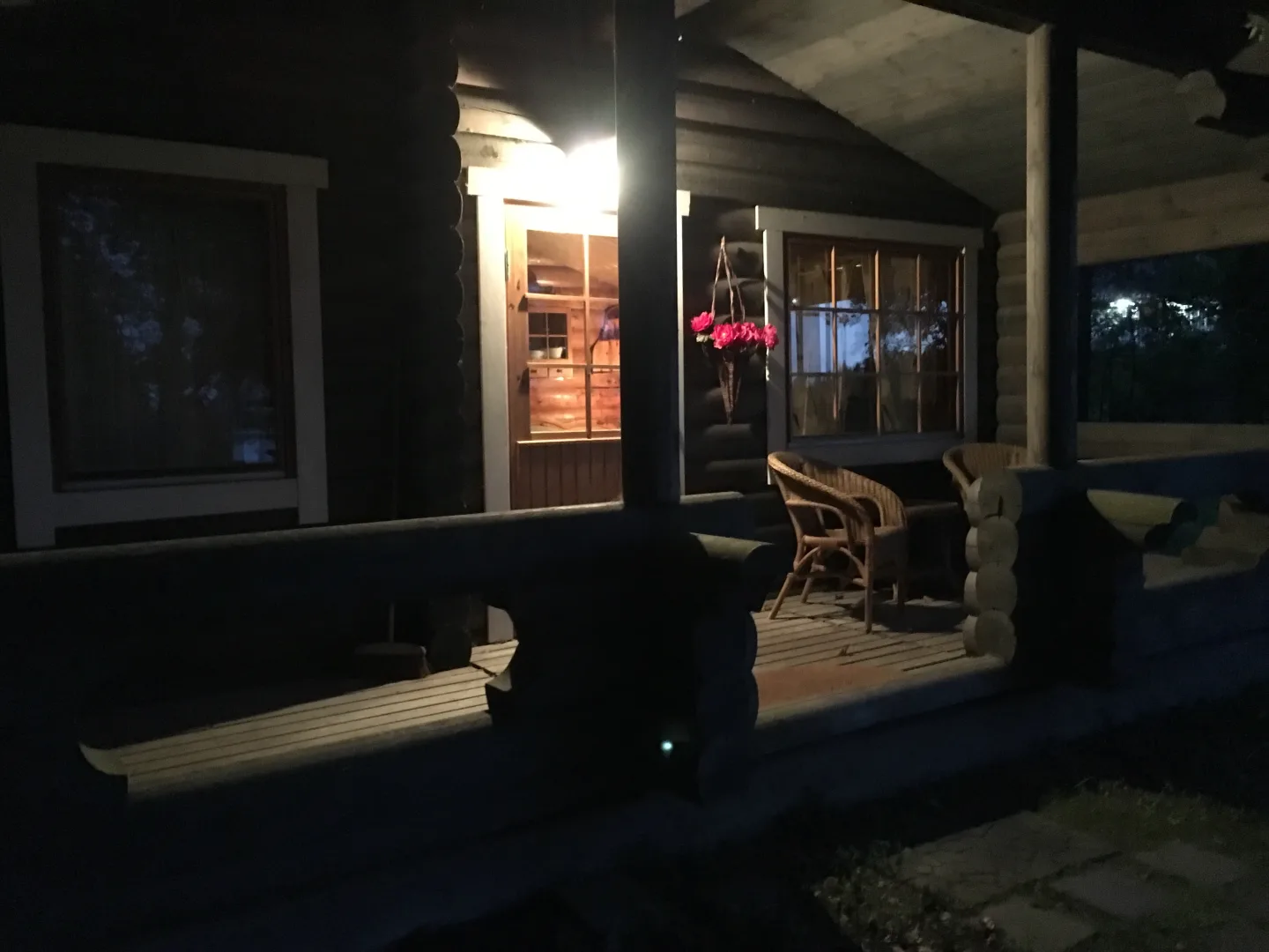 Porche iluminado de una cabaña de madera al anochecer en Finlandia