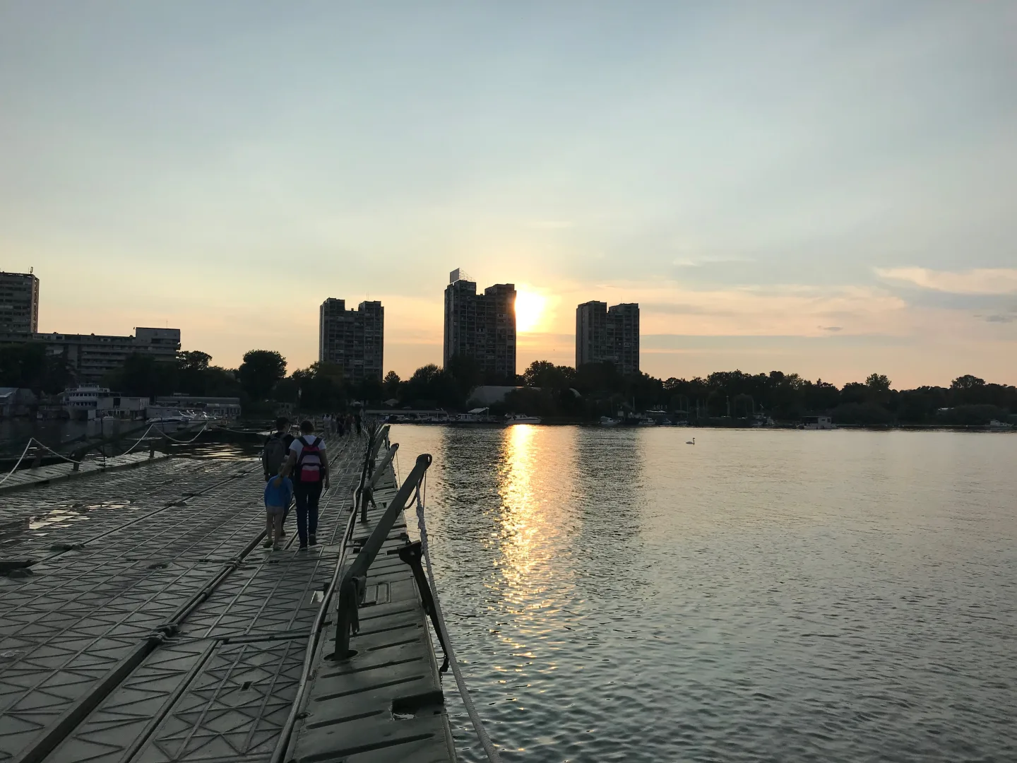 Puente de pontones hacia la playa de Lido al atardecer, con Zemun al fondo